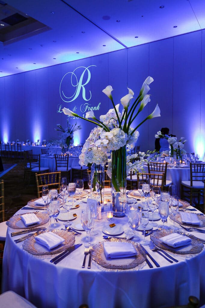 round table at wedding reception with blue lighting and R monogram on wall - margaritaville resort orlando wedding venue